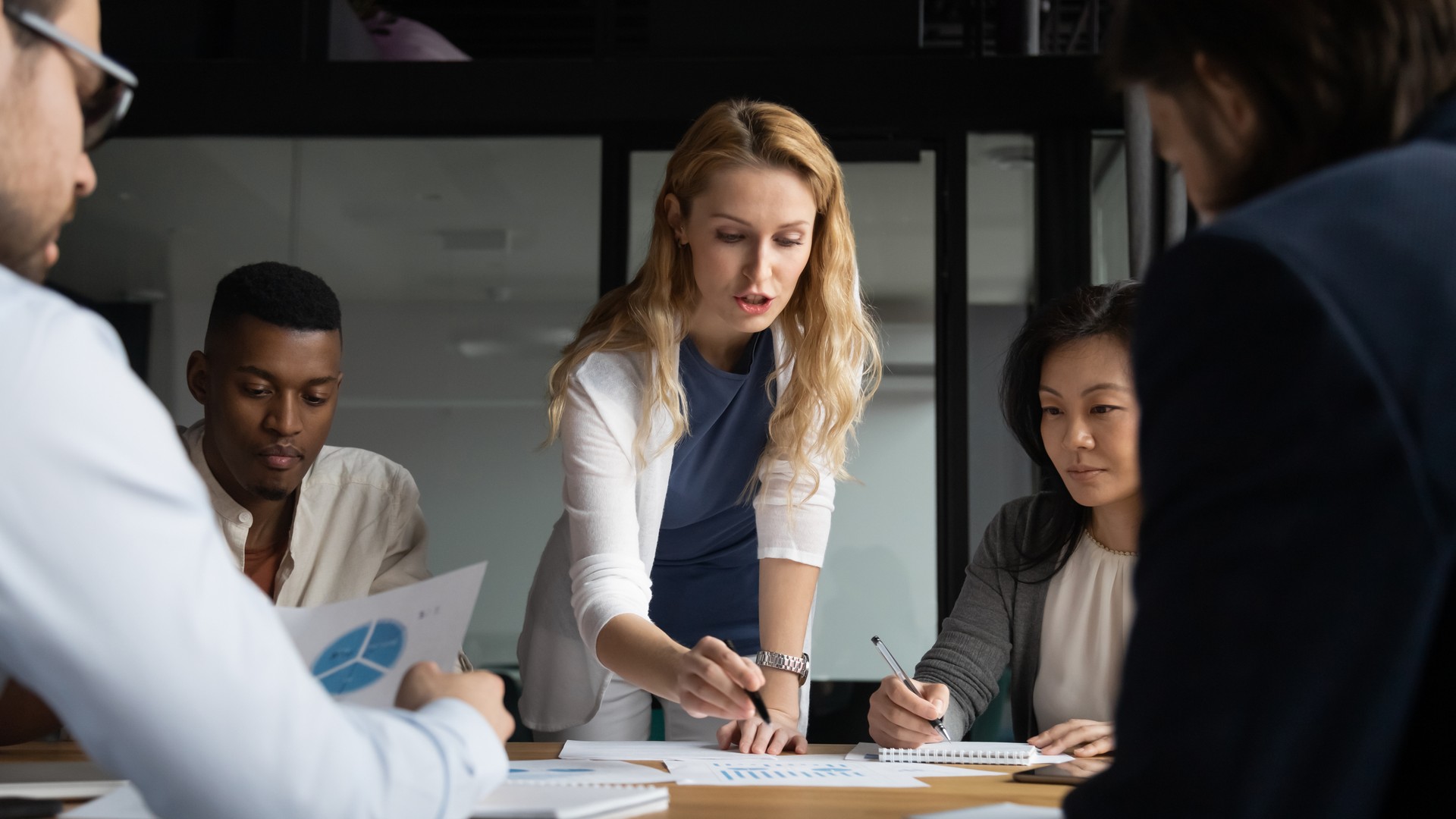 Young businesswoman explaining research results in graphs to colleagues.